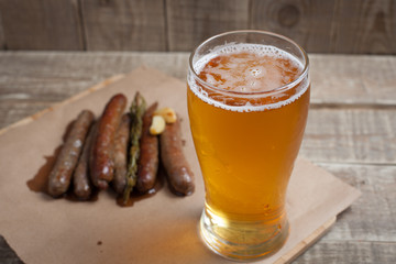 Fried sausages and mug of cold beer on a wooden table. Top view
