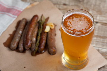 Fried sausages and mug of cold beer on a wooden table. Top view