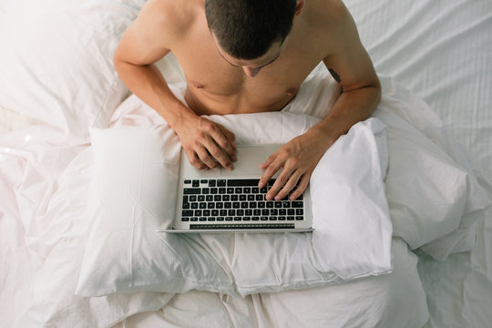 Young man using computer on the bed in the morning