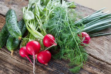 Fresh cabbage, cucumbers, radishes, onions and dill on a wooden background