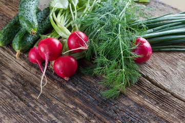 Fresh cabbage, cucumbers, radishes, onions and dill on a wooden background