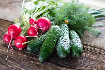 Fresh cabbage, cucumbers, radishes, onions and dill on a wooden background