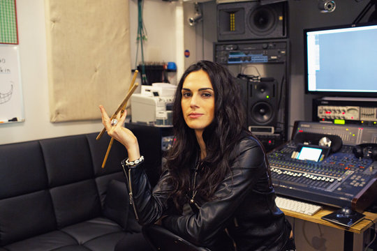 Young woman holding drumsticks in a recording studio
