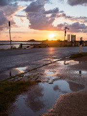 Nasse Straße mit Pfütze an der Ostsee mit Sonnenuntergang, Fehmarn