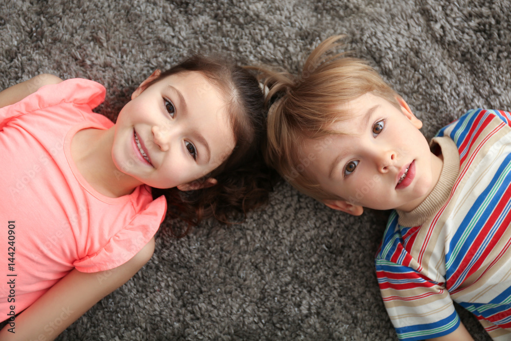 Wall mural Cute little children lying on carpet at home