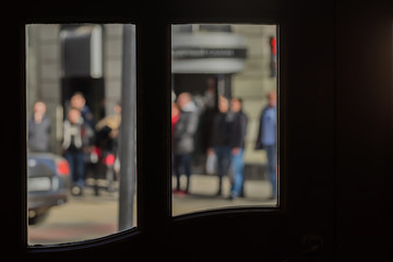 View from a cafe window on a small street of the old city, pedestrians. Intentional motion blur