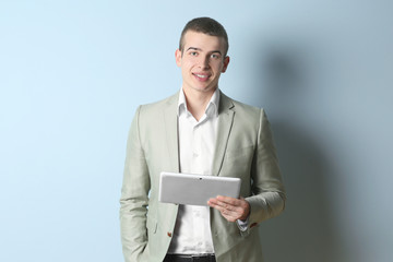 Young handsome man with tablet on light background © Africa Studio