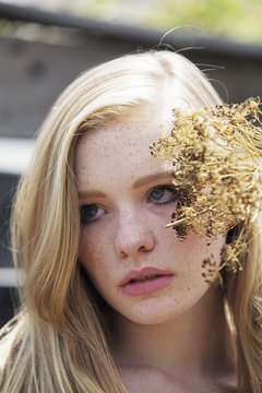 Close up of young woman with dry flowers outdoors
