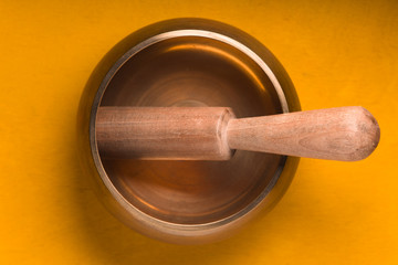 Metal bowl with a wooden stick on a yellow table