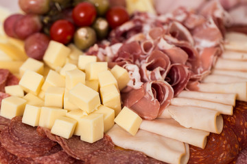 Tray with bacon, cheese cubes, salami, ham; decorated with grapes