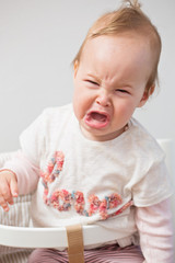One year old baby girl crying while being displeased