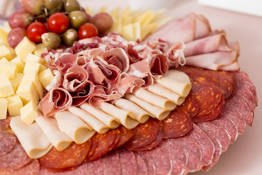 Tray with bacon, cheese cubes, salami, ham; decorated with grapes