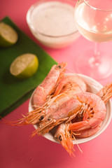 Shrimps in a ceramic bowl, a glass of white wine and a sauce partial blur