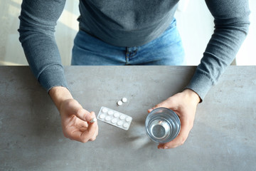 Young man with pills and glass of water at home