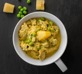 Pineapple, pea and pork stew on black stone background