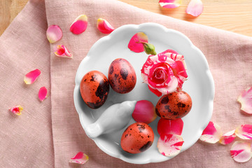 Ceramic plate with decorative bird, Easter eggs and flower on tablecloth