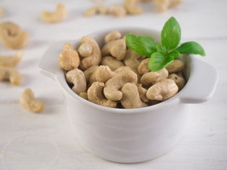 Cashew nuts in the white bowl on wooden table
