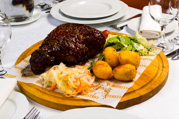 Grilled meat with garnish of vegetables on a wooden round board, studio light