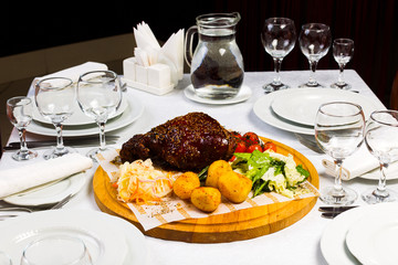 Grilled meat with garnish of vegetables on a wooden round board, studio light
