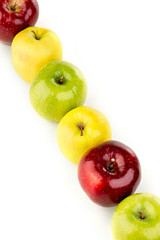 Multicolored apples in a row on a white table