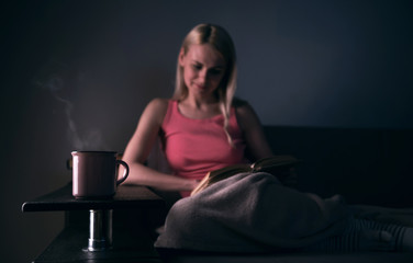 Girl enthusiastically reading a book best-selling house under a rug on a comfortable sofa with a...