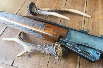 Foto op Plexiglas jachtgeweer en hertenhoorns op houten achtergrond © stsvirkun