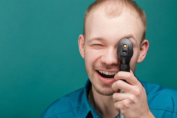 optometrist with ophthalmoscope, instrument to look into eyes by doctor on blue background