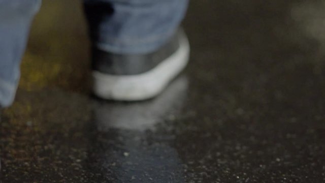 Man walking slow motion on concrete in rain at night
