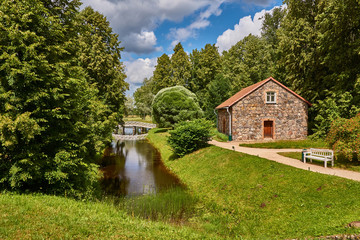 Summer, noon. A pond, a bridge, a stone house and a shop on the grounds of Pushkin's mother's estate. Historical Pushkin places next to the estate of Pushkin's mother. Russia, Pskov region 2015 