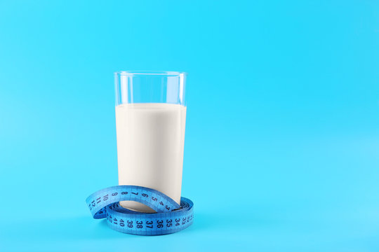 Glass of milk with centimeter on blue background