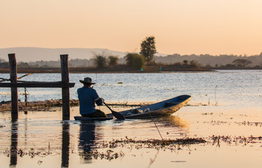 Fisherman on canoe in tropical Bungva lake, Laos