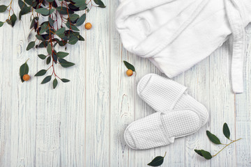 Beautiful composition with bathrobe and slippers on wooden background