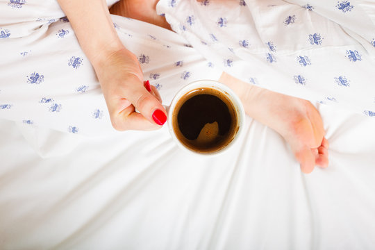 woman on bed with cup of coffee