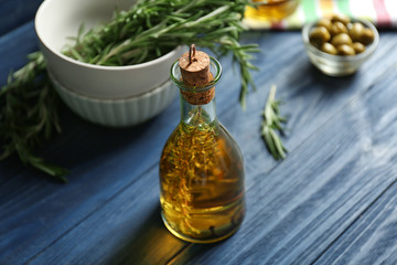 Obraz na płótnie Canvas Bottle with olive oil and herbs on wooden background