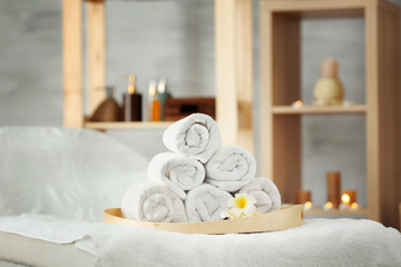 Fototapeta na wymiar Wooden tray with pile of towels in spa salon