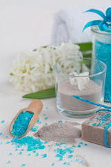 Cosmetic clay powder, homemade clay soap and blue sea salt on white background.