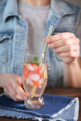Woman with glass of delicious wine spritzer at table