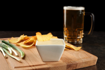 Bowl with beer cheese dip and nacho on wooden board