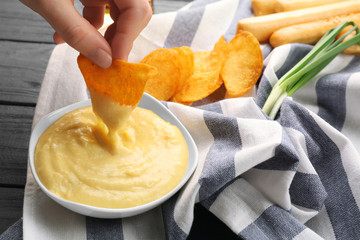Woman hand dipping nacho in beer cheese dip