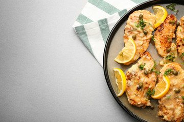 Plate with tasty Italian chicken piccata on table