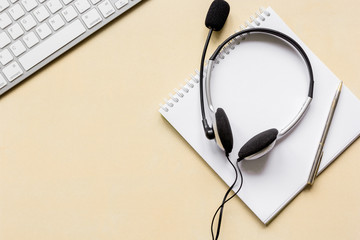 Office desk with headset and keyboard brown background top view mockup