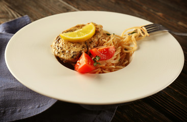 Delicious spaghetti with chicken, tomatoes and lemon on plate