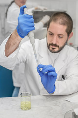 Two scientists in the laboratory filling test tubes with pipette