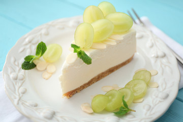 Tasty cheesecake slice with grapes on plate