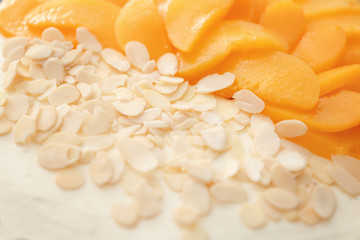 Tasty cheesecake with fruit slices and nut chips, closeup
