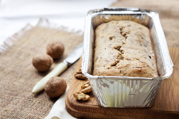 Banana cake with walnuts and dark chocolate in aluminum baking tin