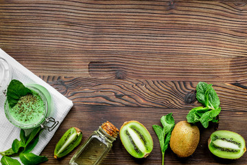woman cosmetic set with kiwi scrub table background top view mock up