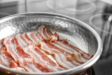 Pan with strips of bacon on stove