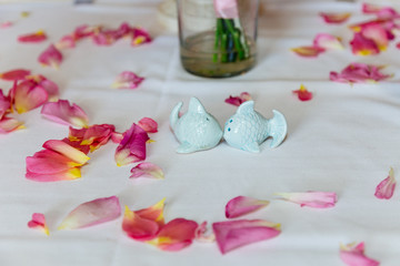 Fototapeta na wymiar Cute fish saltwort and pepper on the white tablecloth with rose petals