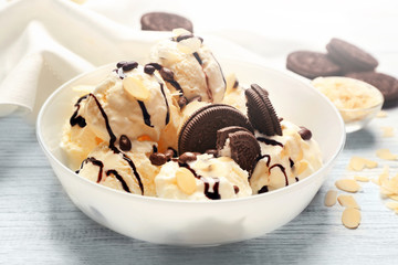 Delicious ice cream with chocolate cookies, candies and nut flakes in bowl